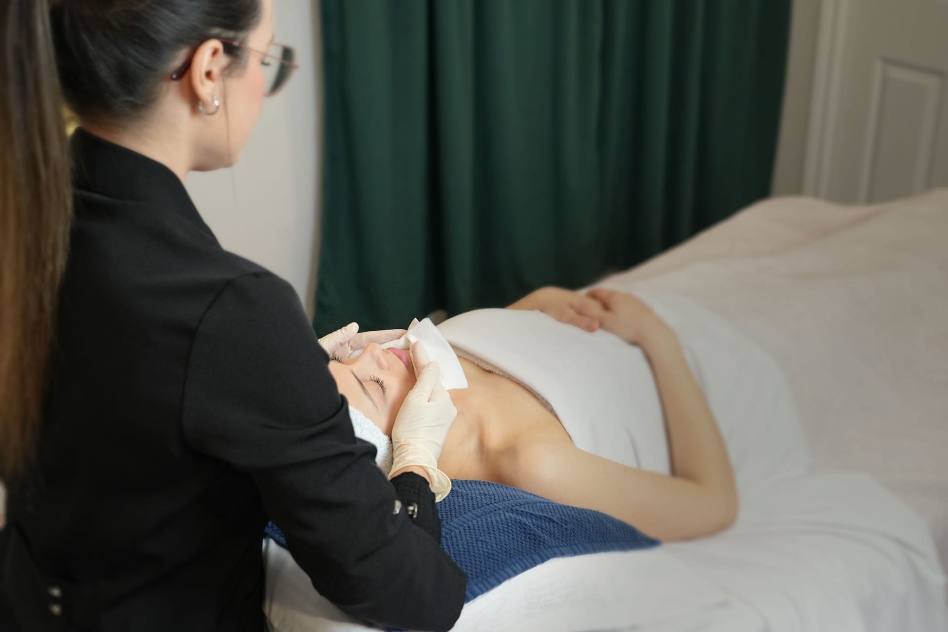 Une femme allongée reçois un soin du visage en clinique d'esthétique