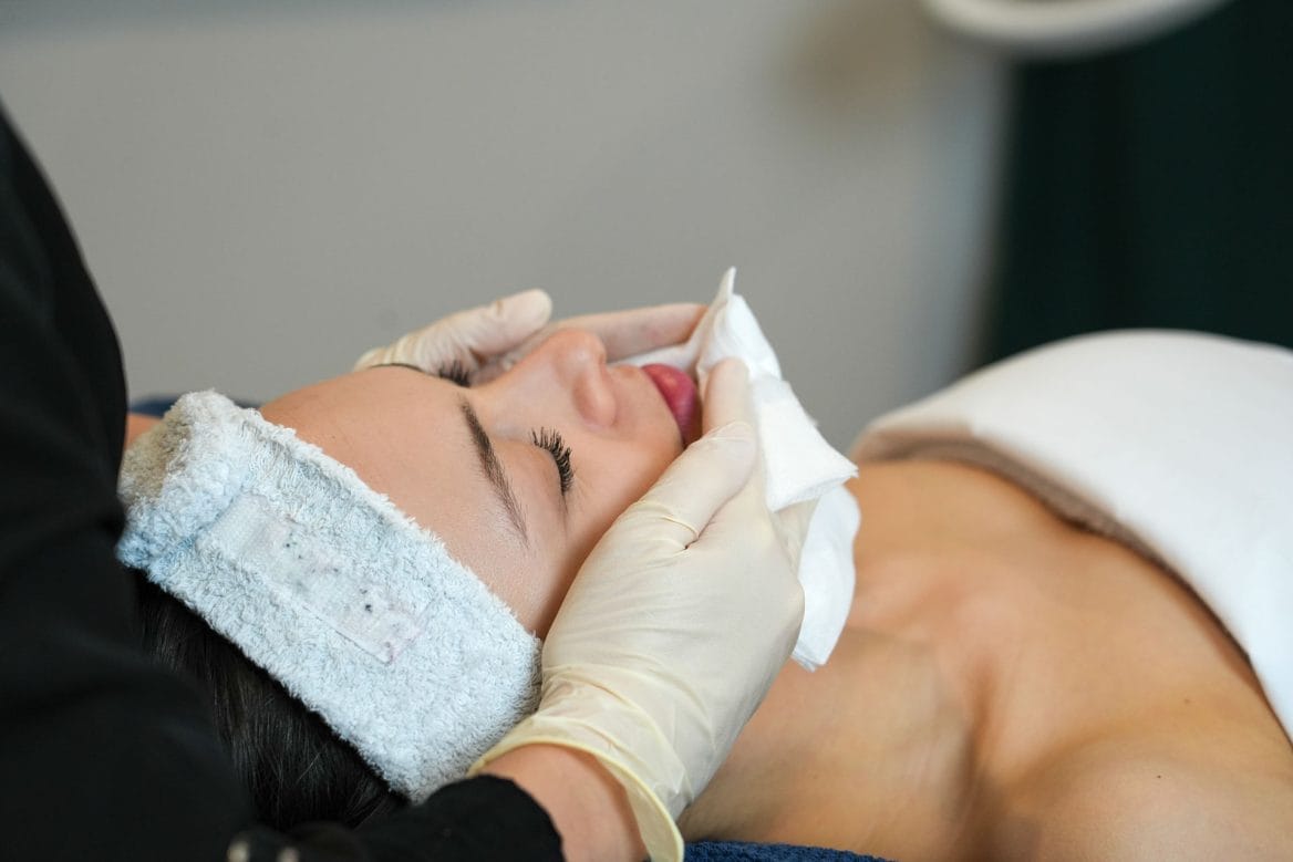 Une femme couchée les yeux fermés reçoit un soin du visage